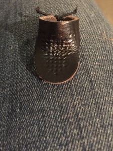 Leather thimble worn on the inside of the middle finger