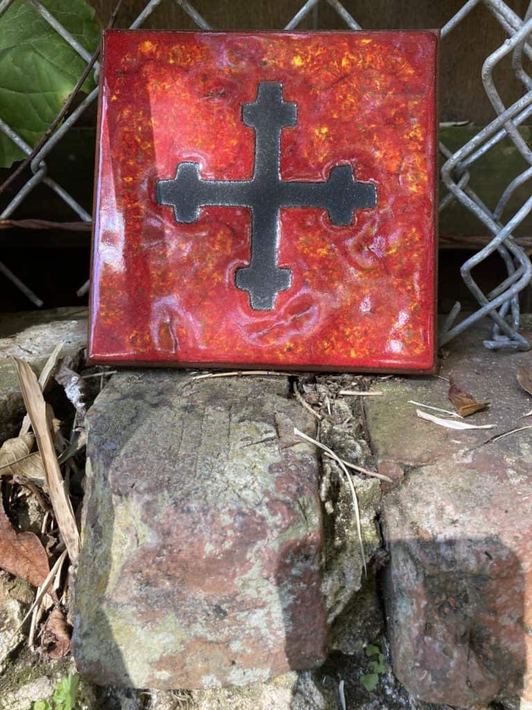 A red tile with an imprinted cross to remind us of the spiritual in examining white privilege 
