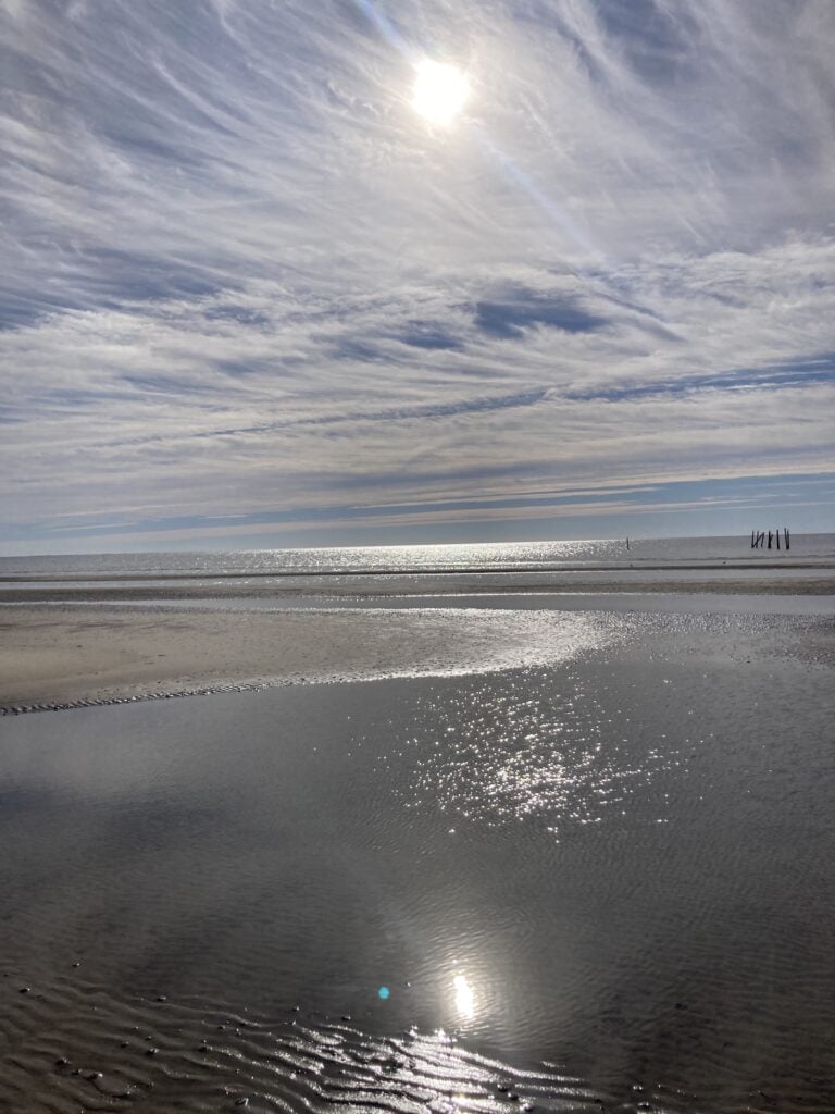 The Mississippi Gulf Coast under a swirling cloud sky with sandbars and tidal pools in the foreground. Taken during Black History Month. 