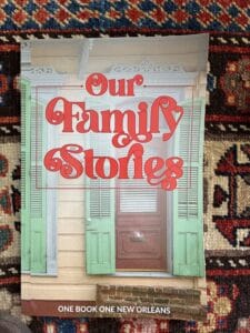 Cover of "Our Family Stories" by OBONO featuring a traditional New Orleans cottage with green shutters , beige walls, and a wooden door.